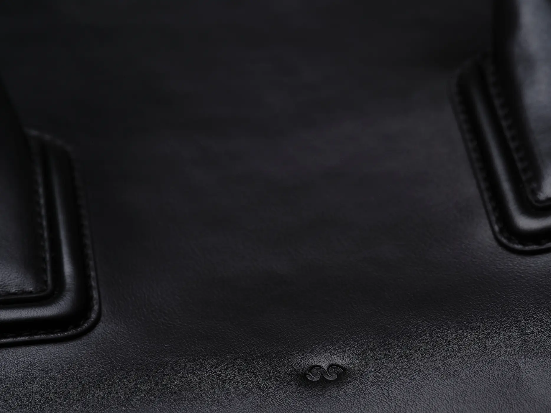 Close-up of black leather with the embossed SIÉ STUDIO monogram